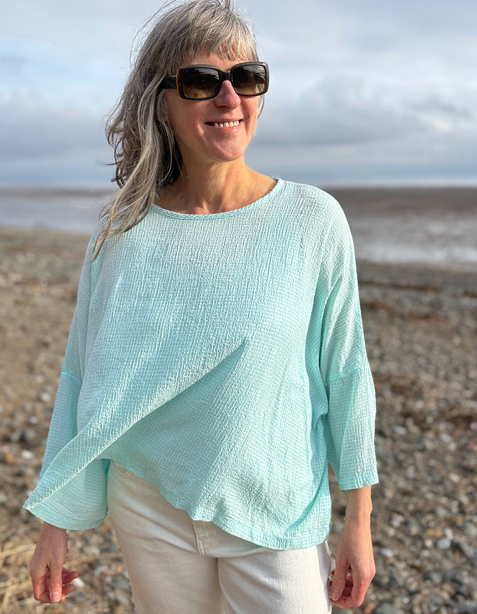 woman wearing loose fit mint top with cream jeans