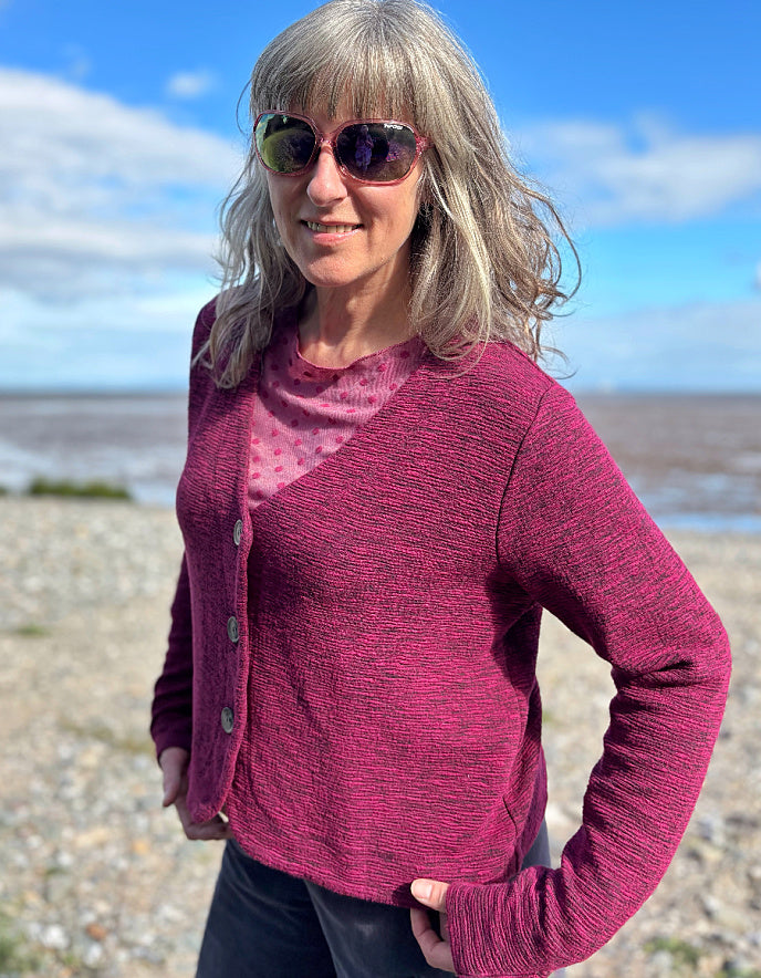 Woman wearing a pink cardigan and sunglasses on a beach