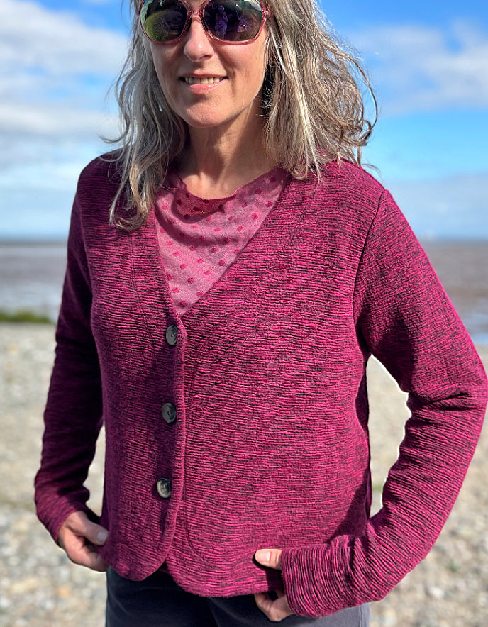 Woman wearing a pink cardigan over a pink top on a beach