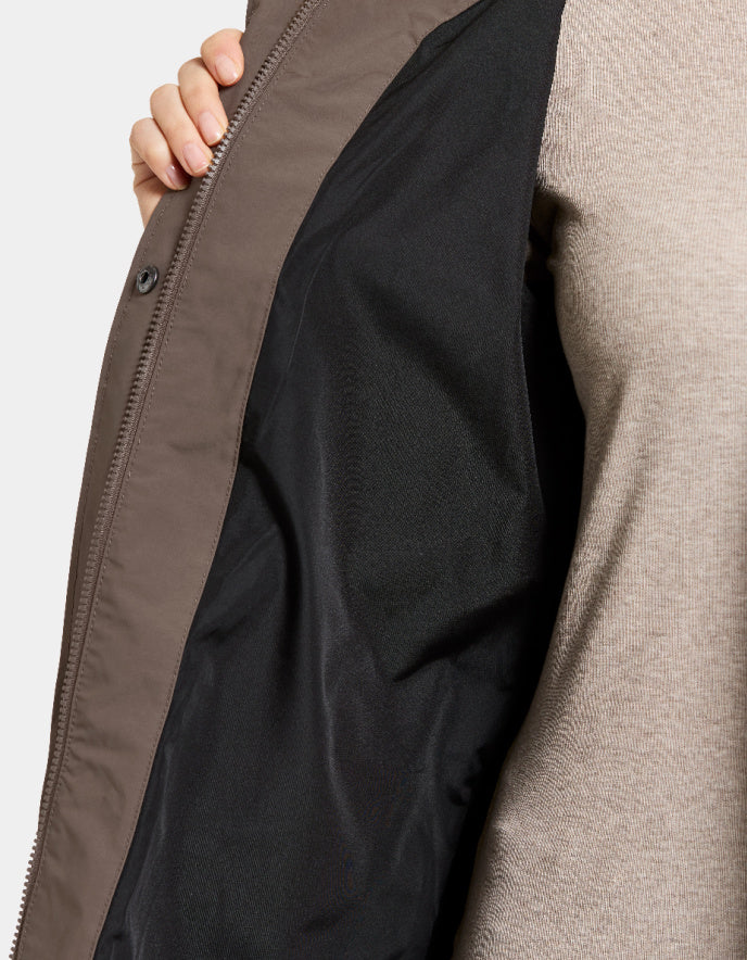 Close-up of a person wearing a beige jacket with a black lining, focusing on the zipper area.