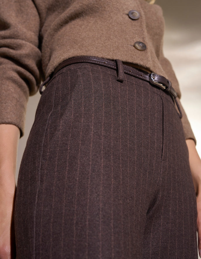 Brown pin stripe pants worn by a person on a white background