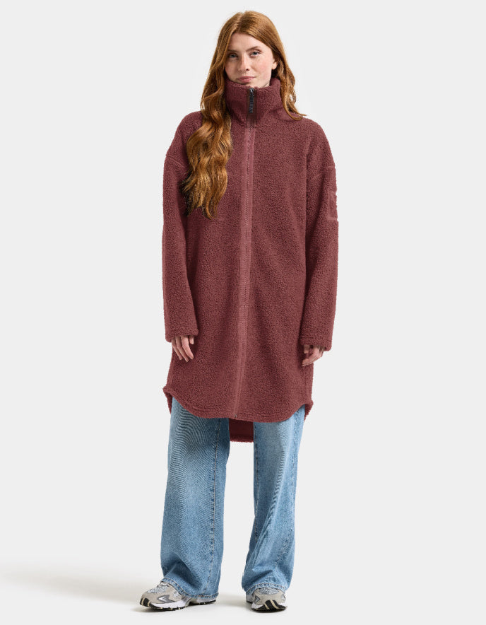 Woman wearing a long burgundy fleece sherpa pile coat on a white background jacket