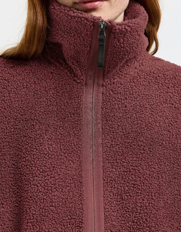 Woman wearing a long burgundy fleece sherpa pile coat on a white background jacket