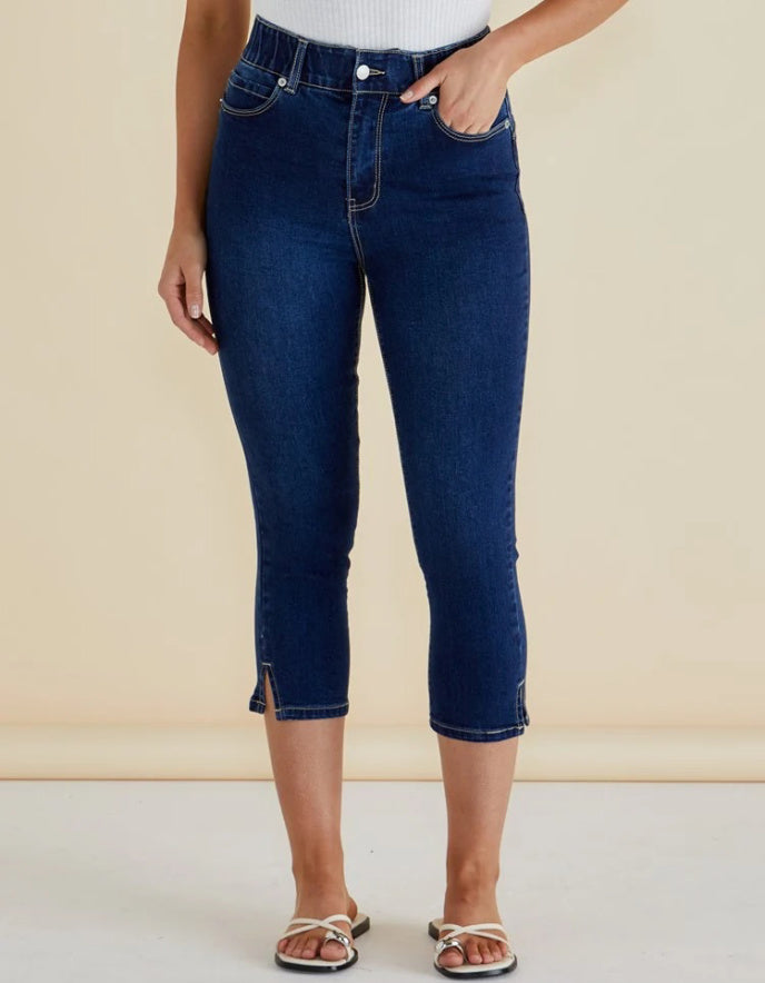 Person wearing dark blue jeans on a beige background
