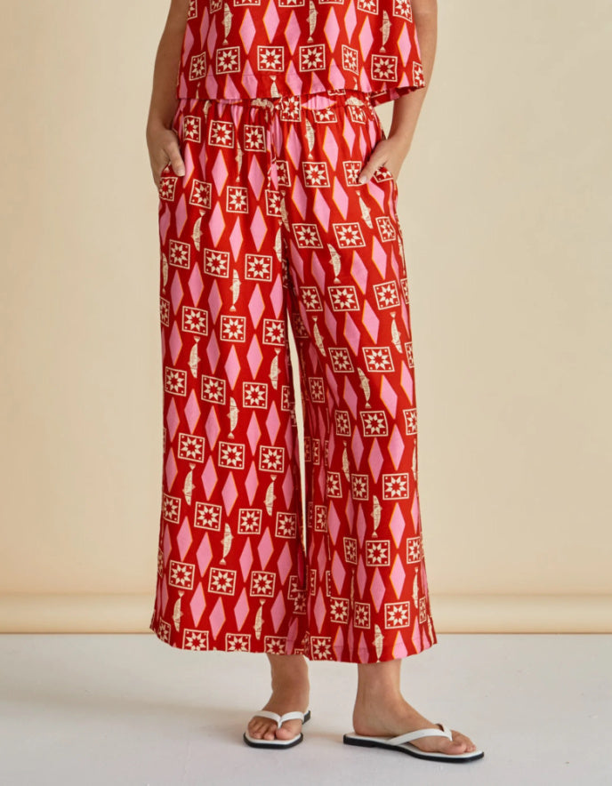Person wearing a red patterned outfit on a beige background
