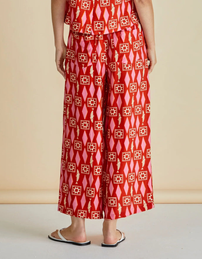 Person wearing a red patterned outfit on a beige background