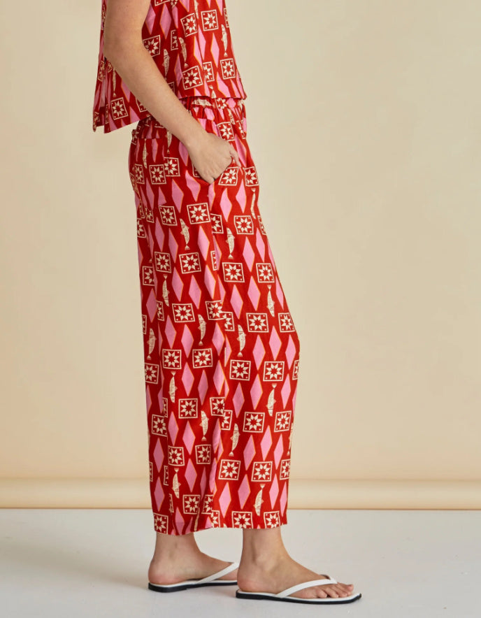 Person wearing a red patterned outfit against a beige background