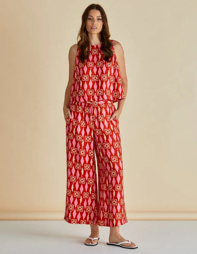 Woman wearing a red patterned jumpsuit against a beige background