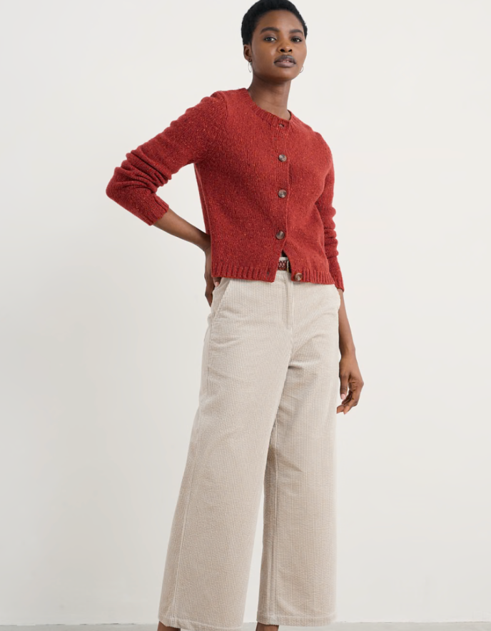 Person wearing a red knitted donegal tweed cardigan with a neutral background