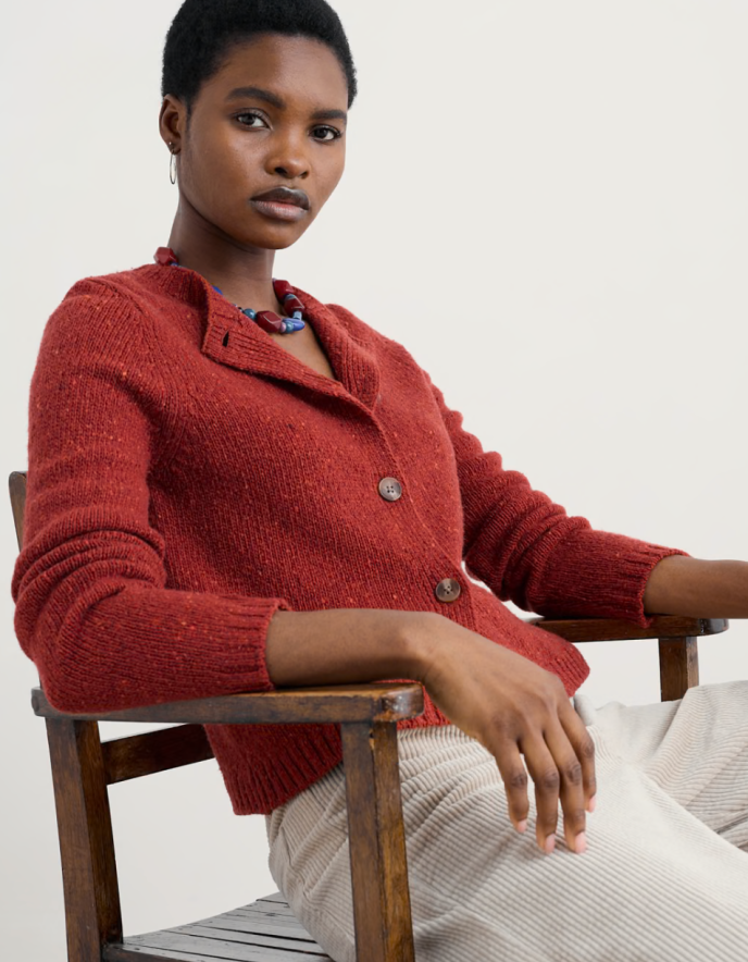 Person wearing a red knitted donegal tweed cardigan with a neutral background