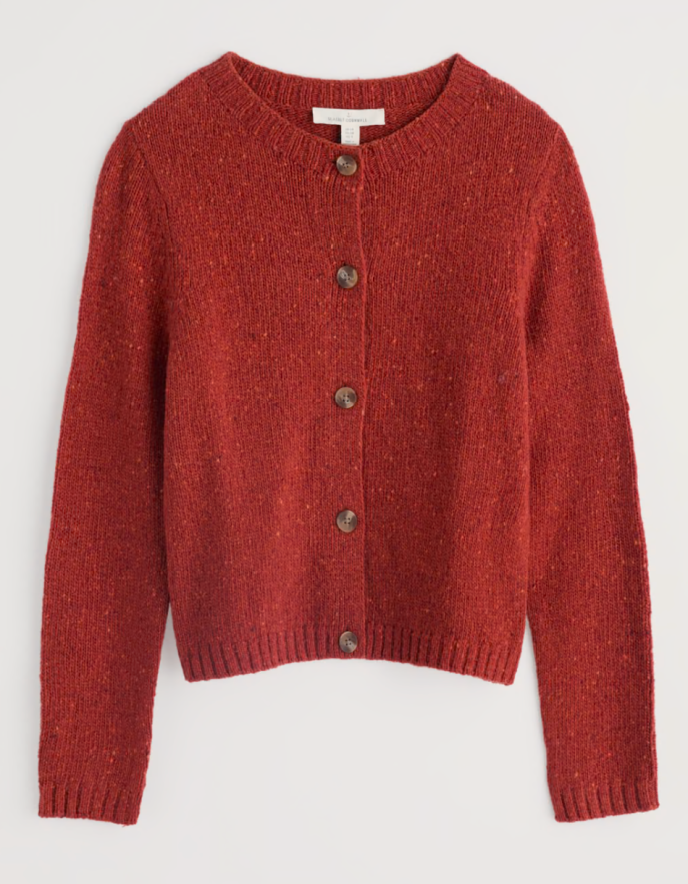 Person wearing a red knitted donegal tweed cardigan with a neutral background