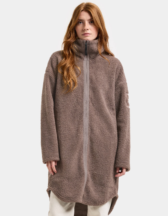 Woman wearing a brown long sherpa pile fleece coat on a white background