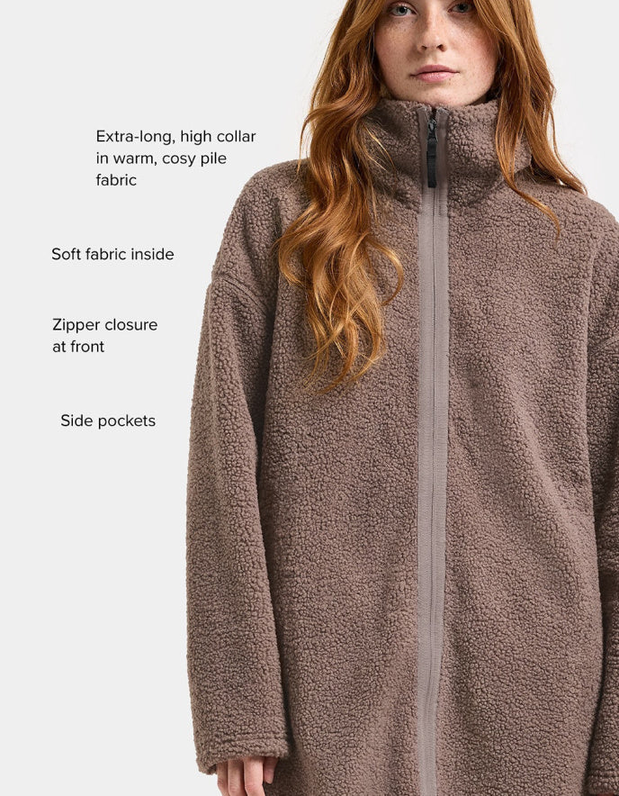 Woman wearing a brown long sherpa pile fleece coat on a white background