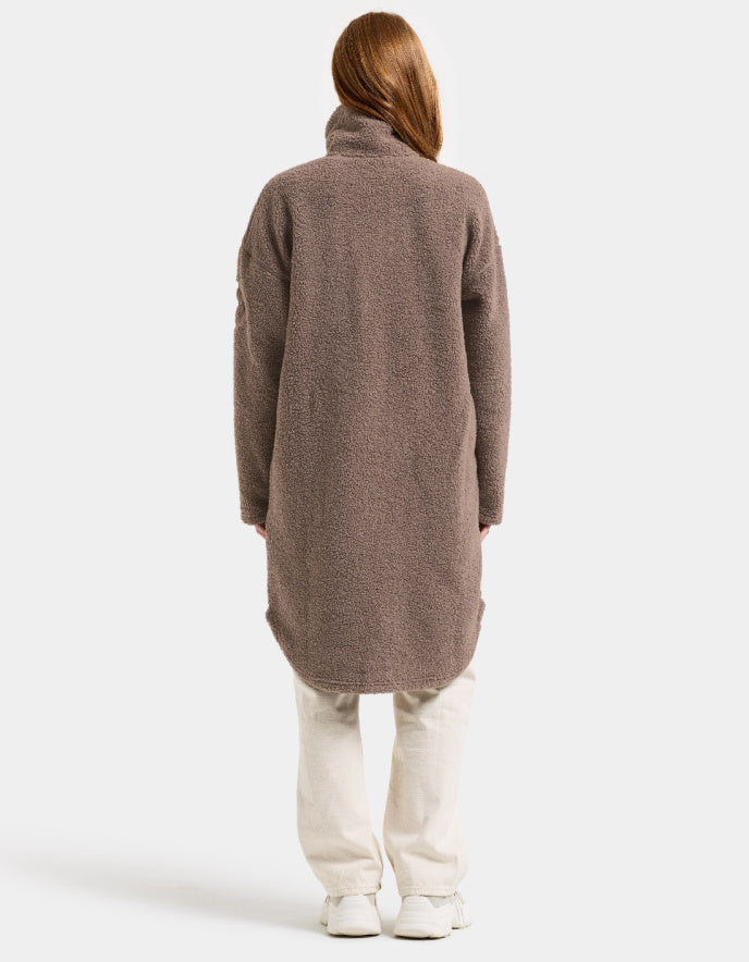 Woman wearing a brown long sherpa pile fleece coat on a white background