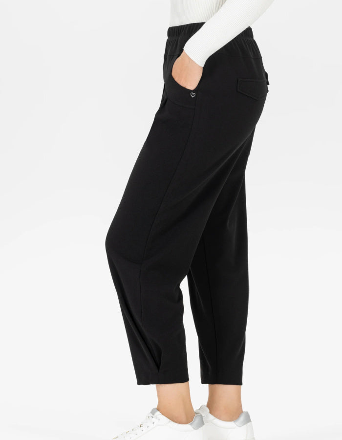 Black cropped pants with a side pocket and side seam detail, shown on a model from the side wearing a white top and white sneakers against a white background.