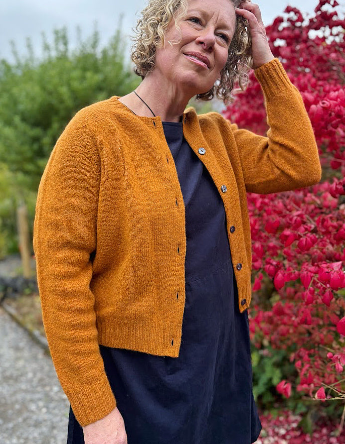Woman wearing a mustard yellow knitted cardigan in a garden setting