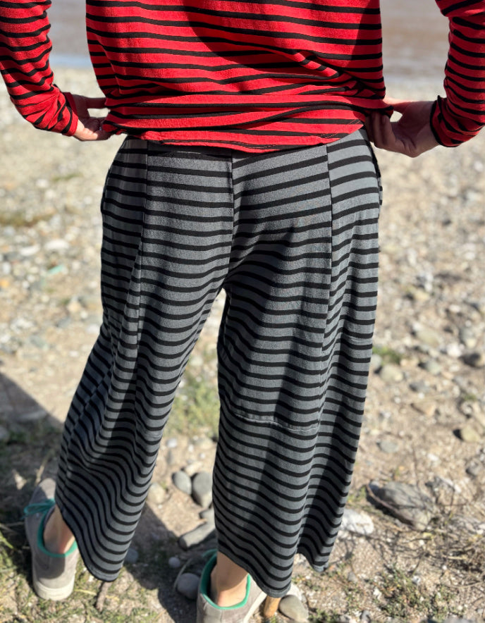 Person wearing a red and black striped shirt and gray and black striped pants on a rocky ground.