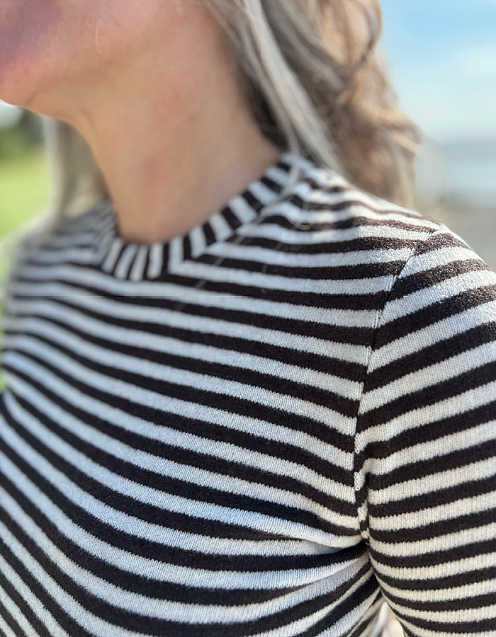 Person wearing a black and white striped shirt with a blurred background