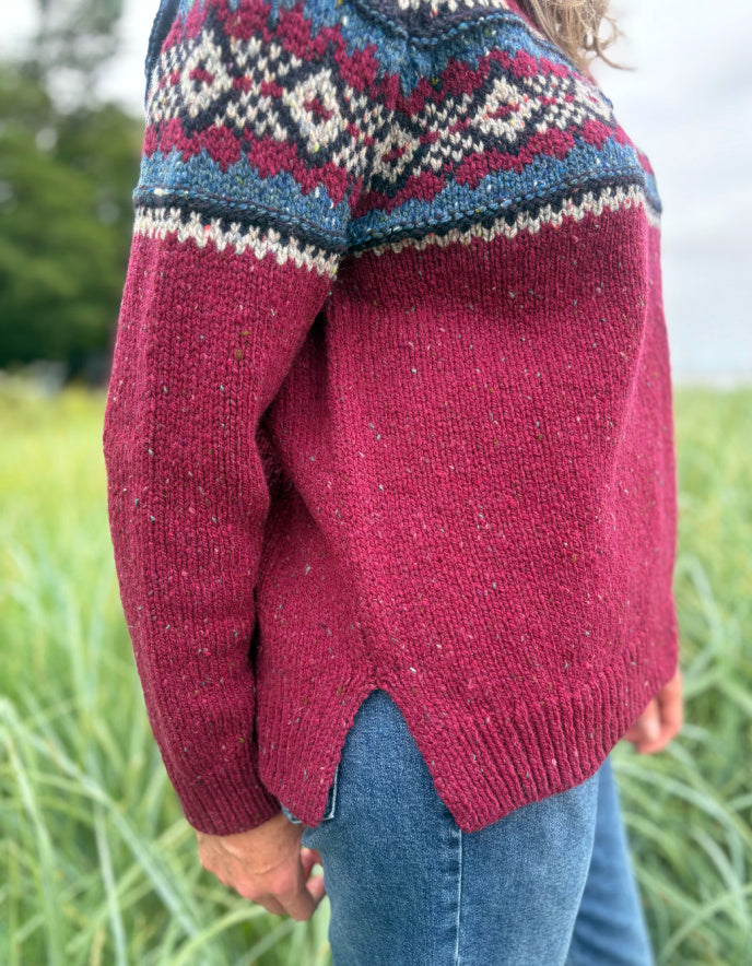 Person wearing a red Fair Isle patterned sweater standing in a grassy field