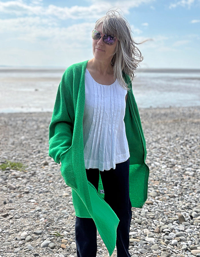 Woman wearing a wool green cardigan and sunglasses on a beach