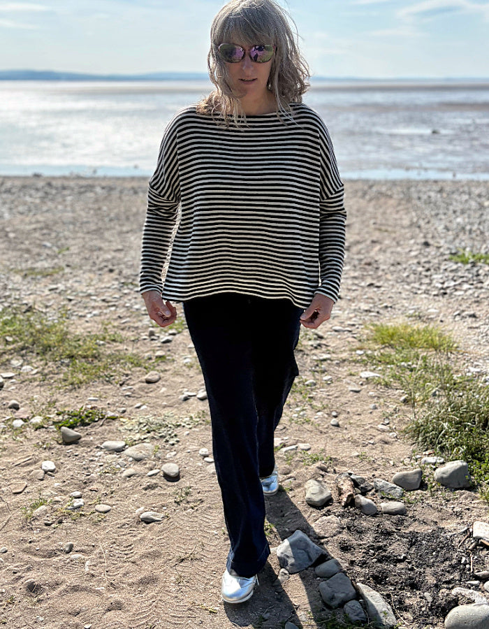 Person wearing a striped sweater and sunglasses on a beach