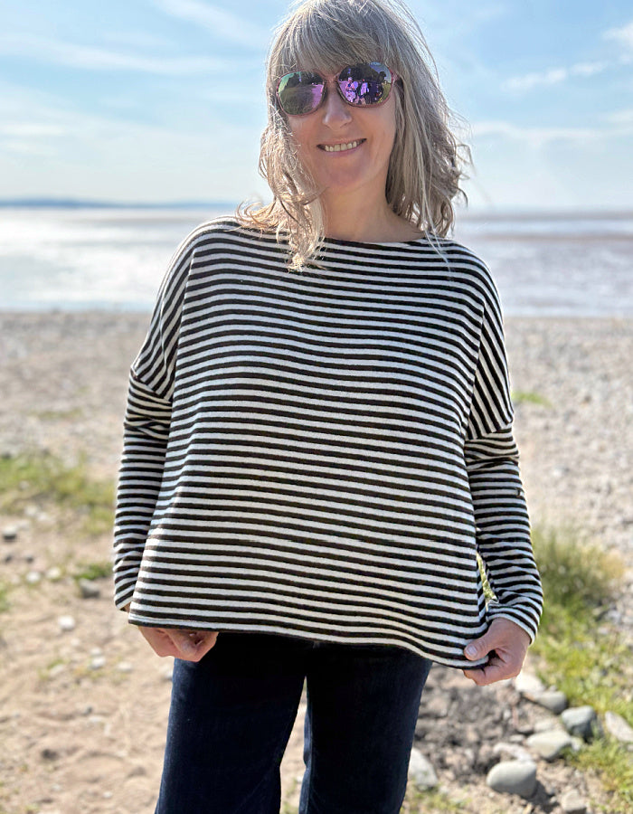 Person wearing a black and white striped sweater on a beach