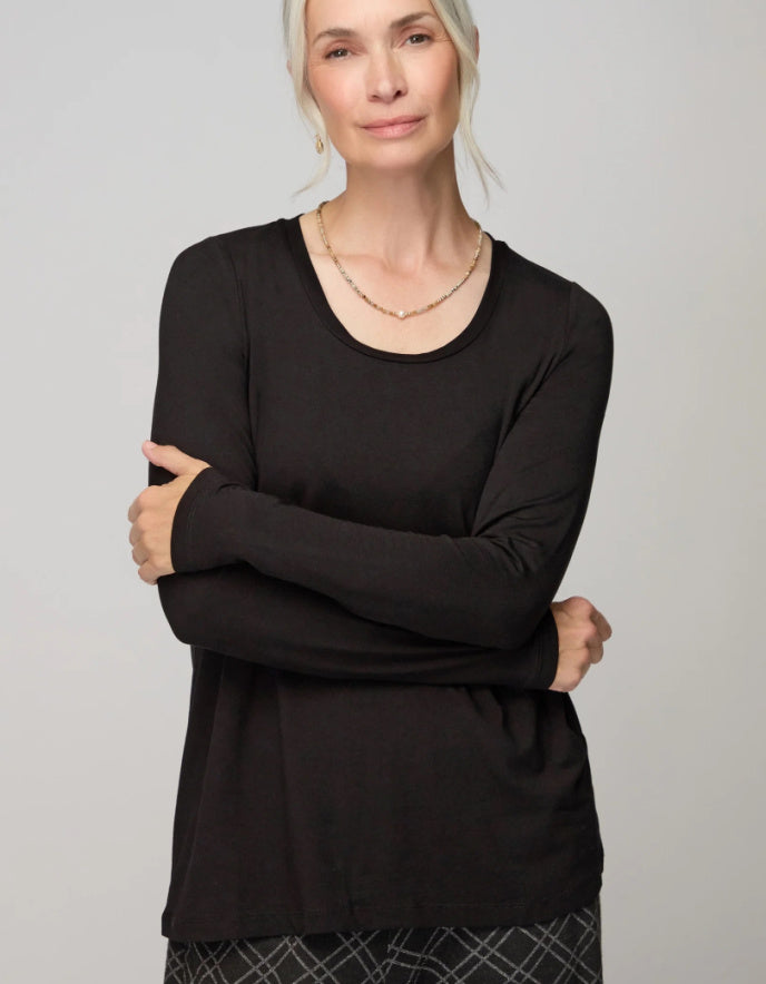 Woman wearing a black long-sleeve top against a plain background