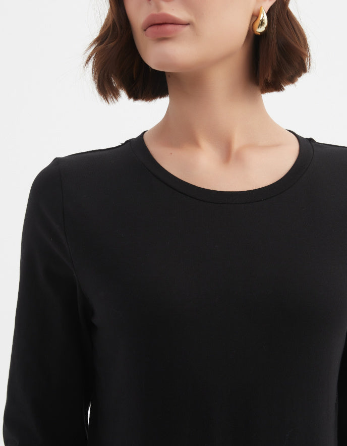 Black long-sleeve top worn by a person on a white background