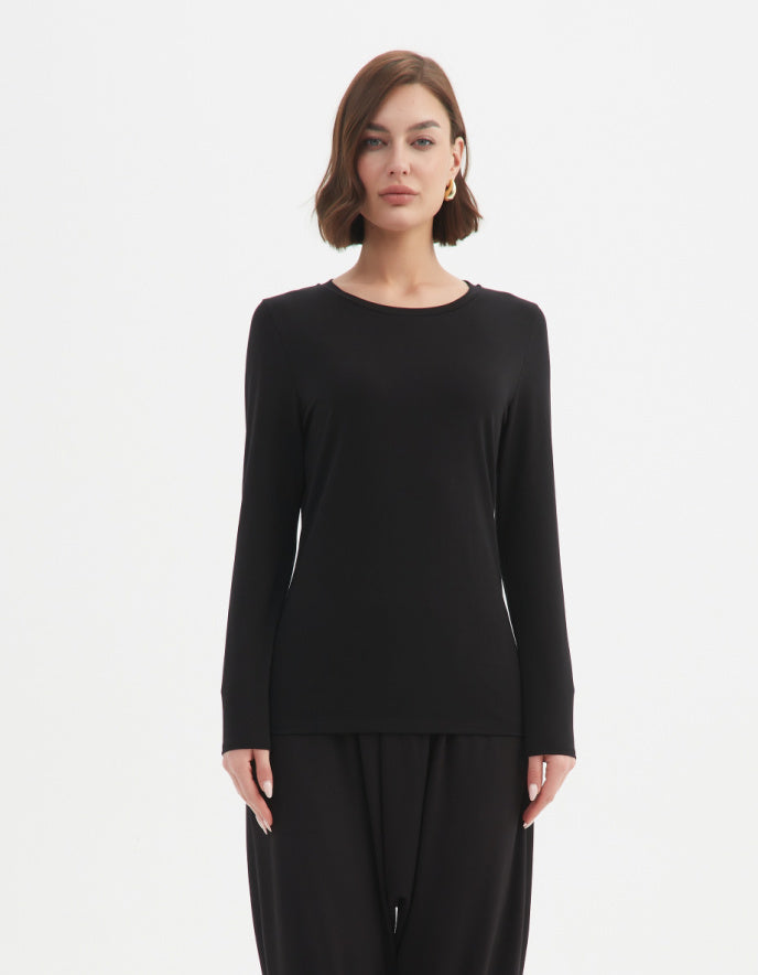 Woman wearing a black long-sleeve top and black pants on a white background