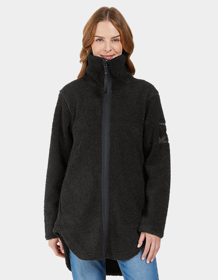 A woman smiling, wearing a black full zip fleece jacket with a stand-up turtle neck and curved hemline. The jacket is displayed on a plain background.