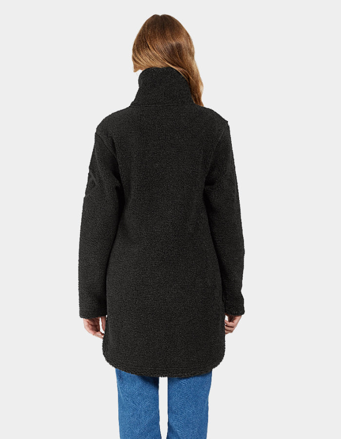 A woman smiling, wearing a black full zip fleece jacket with a stand-up turtle neck and curved hemline. The jacket is displayed on a plain background.