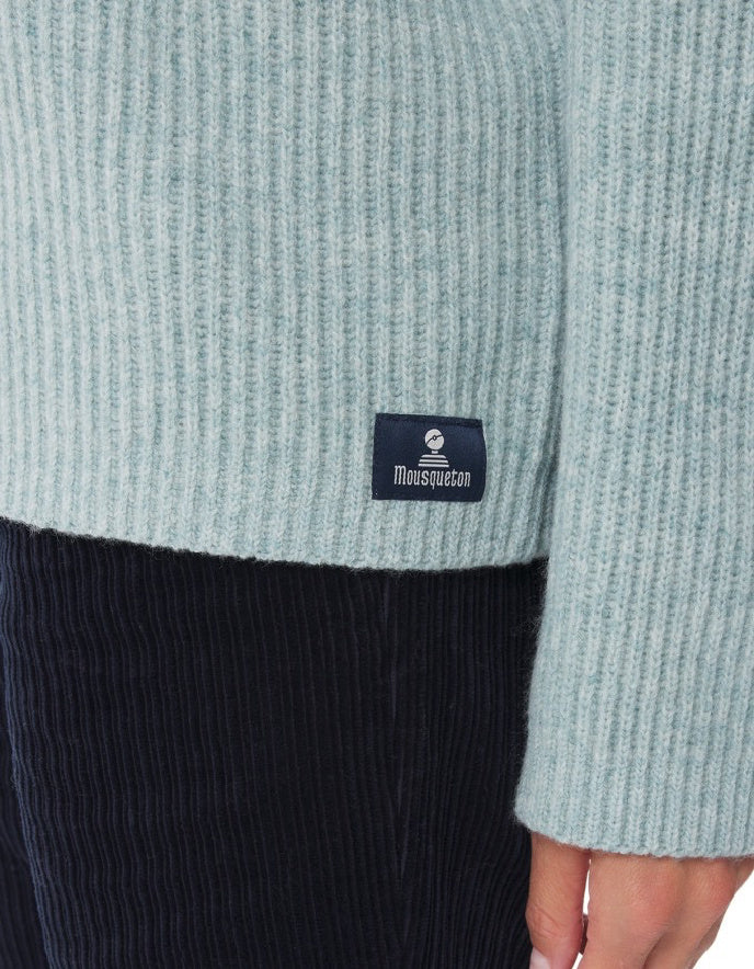 Close-up of a light blue sweater with a brand label on a white background