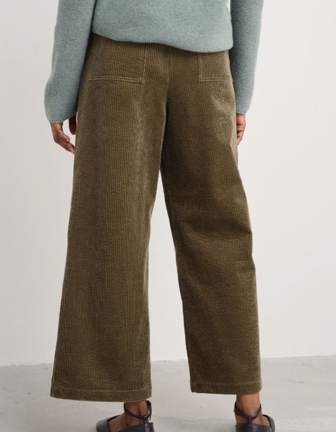 Person wearing brown corduroy pants and a light green sweater on a white background