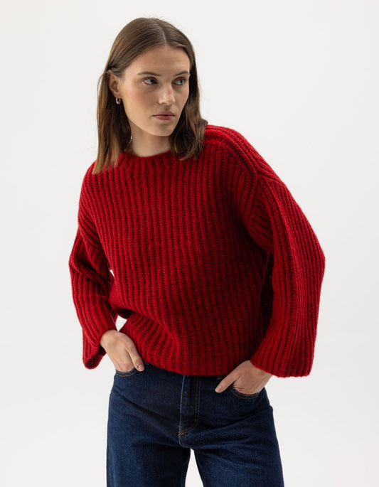 Person wearing a red sweater and blue jeans on a white background
