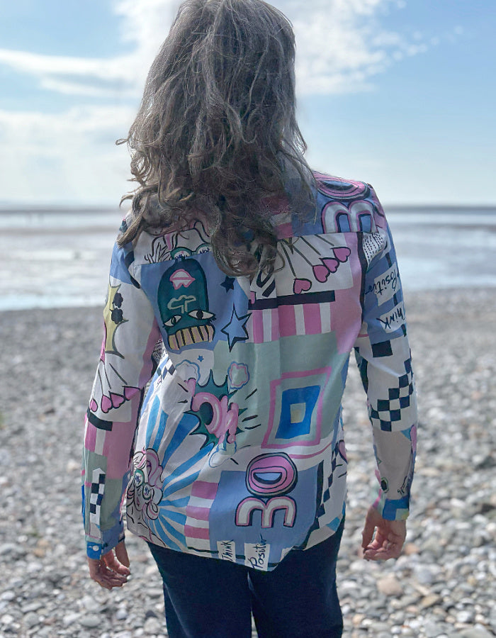 Person wearing a colorful, patterned cartoon print shirt on a beach