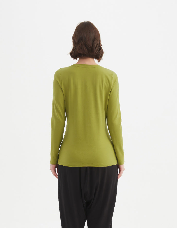 Person wearing a green long-sleeve top and black pants on a white background