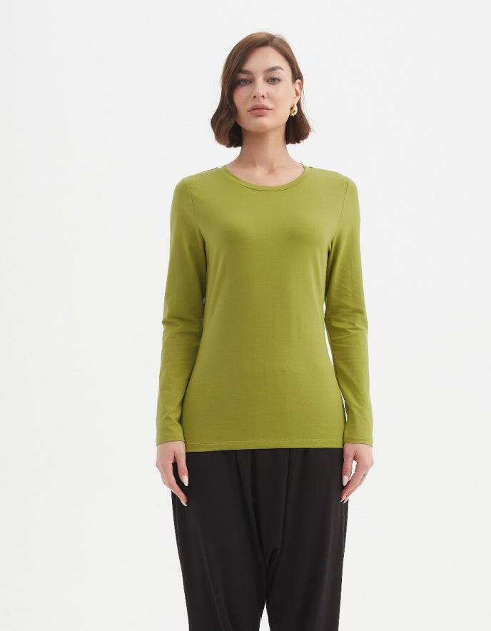 Woman wearing a green long-sleeve top and black pants on a white background