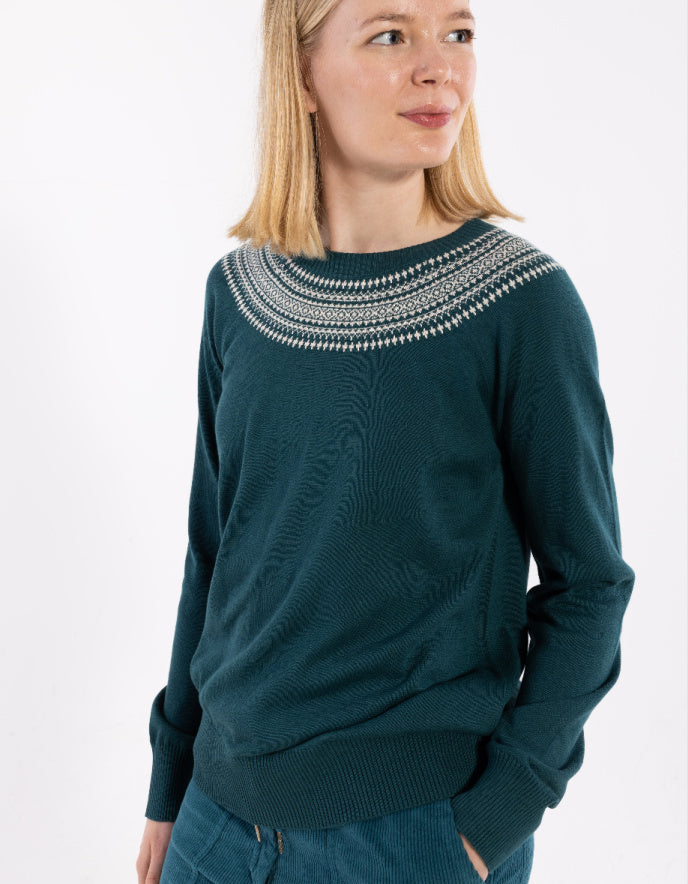 Woman wearing a dark green sweater with a patterned neckline on a white background