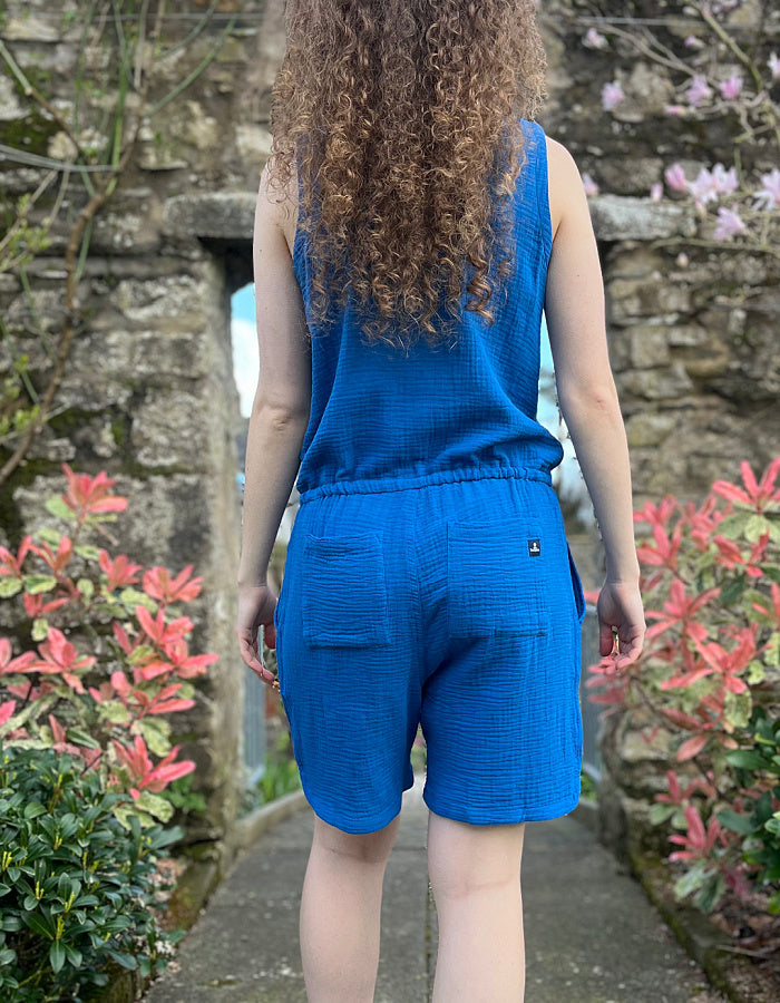 cotton short jumpsuit with cross over front panel and front and rear pockets and adjustable drawstring waist in gauzy cheesecloth blue cotton