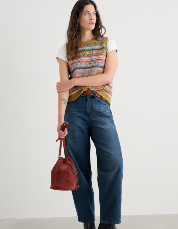 Woman wearing a colourful fair Isle Tank top over a white shirt on a plain background