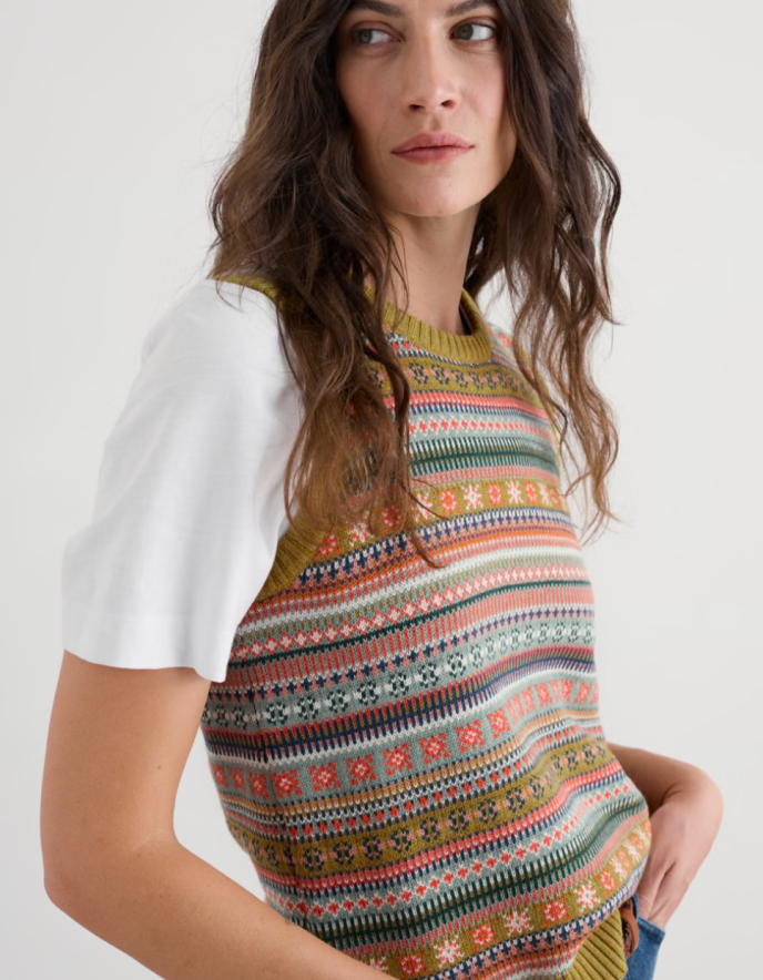 Woman wearing a colourful fair Isle Tank top over a white shirt on a plain background