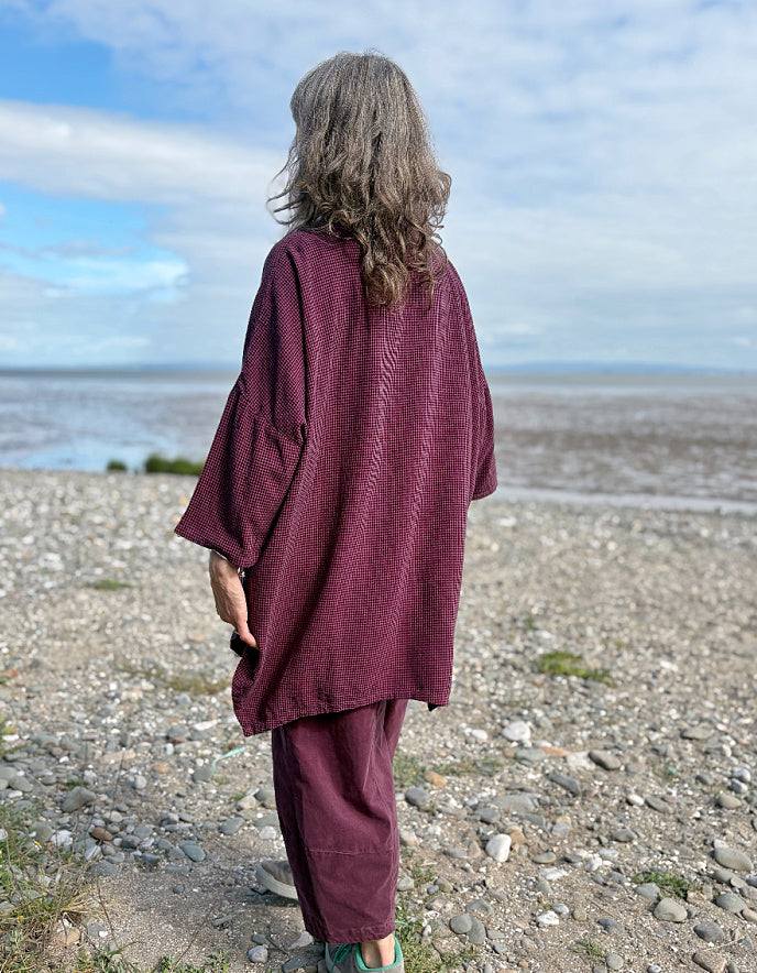 woman wearing oversized purple burgundy tunic and lantern shaped trousers