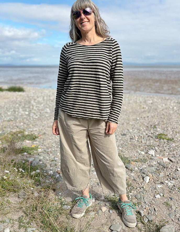 Woman standing on a beach wearing a striped shirt and sunglasses