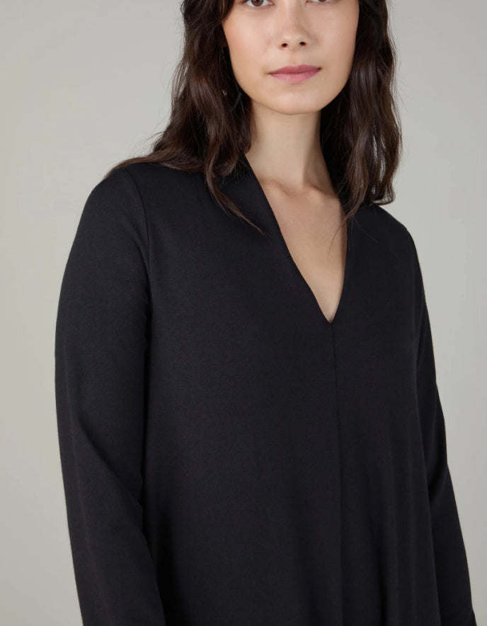 Woman wearing a black v neck bubble dress against a neutral background