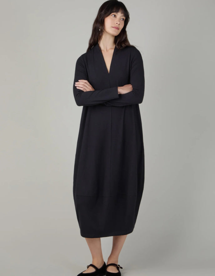 Woman wearing a black v neck bubble dress against a neutral background