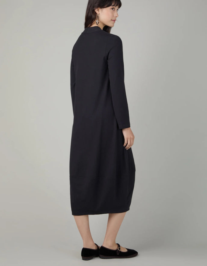 Woman wearing a black v neck bubble dress against a neutral background