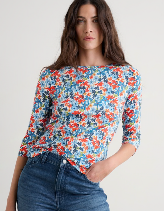 Woman wearing a colourful floral cotton jersey t shirt top with a plain background