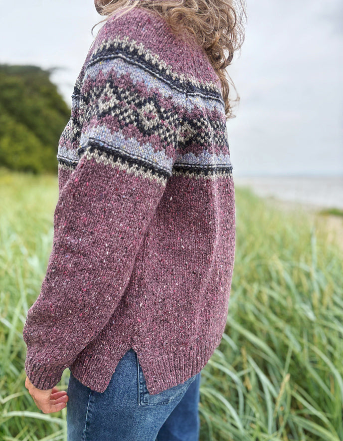 Person wearing a patterned berry Fair Isle sweater and sunglasses in a field