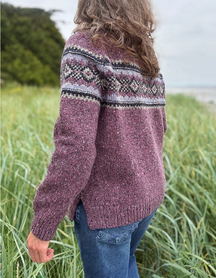 Person wearing a patterned berry Fair Isle sweater and sunglasses in a field