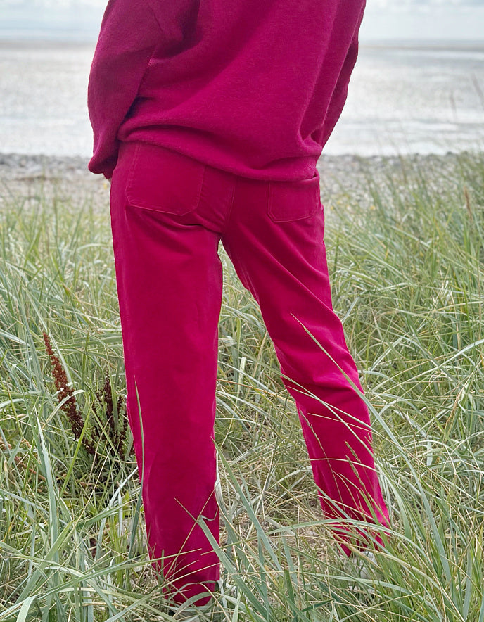 Person wearing bright pink velvet pants and a matching top standing in grass.